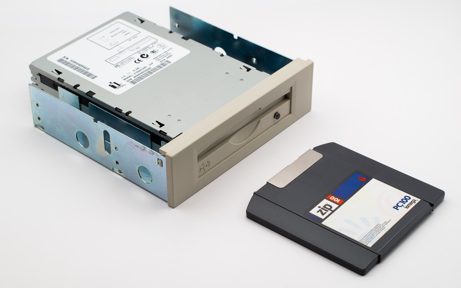 An internal Zip drive beside a black 100MB Zip disk cartridge